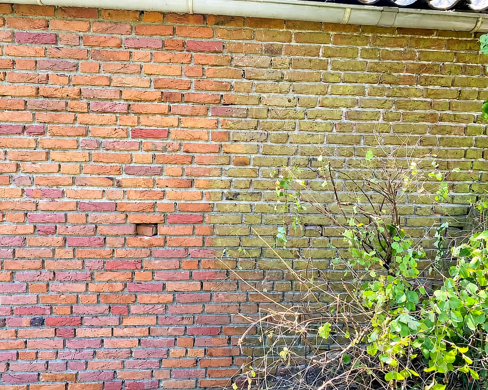 Gevel half gereinigd, links schoon en rechts nog vervuild